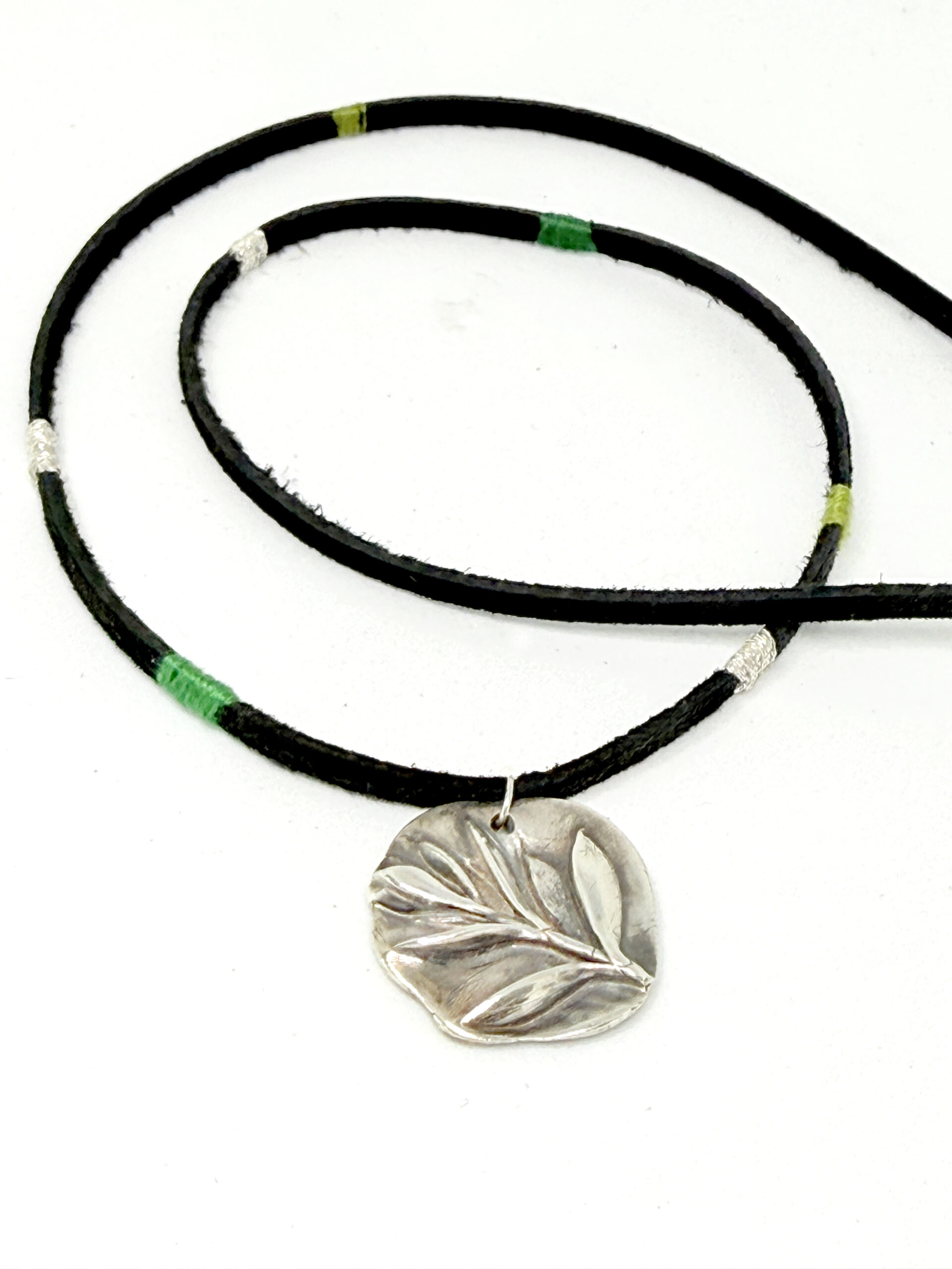 botanical silver pendant on a silk wrapped cord